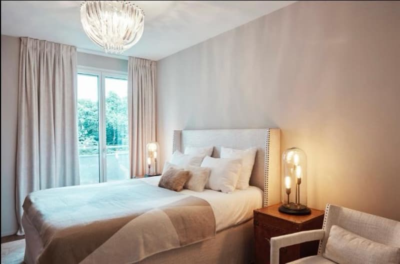 spacious bedroom, large bed, chandelier, bedside lamps, nightstand, glass lamp, armchair, large windows, view of outdoors