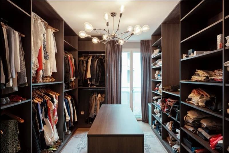 walk-in closet, chandelier, wooden desk, open wardrobes, various clothing items, windows with curtains