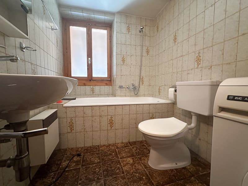 Bathroom: bathtub, sink, toilet, tile walls, white fixtures, wooden window frame