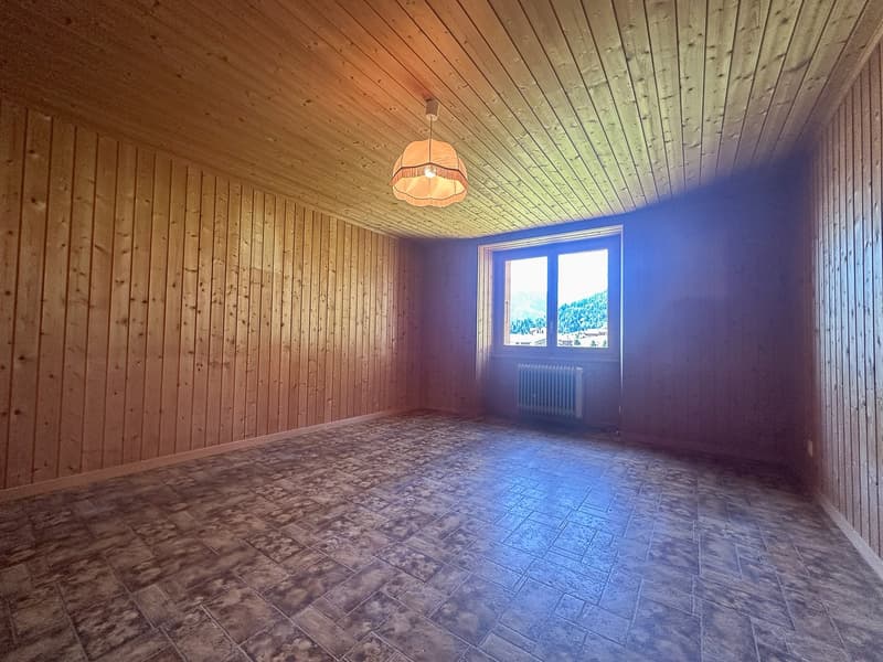 room with wooden walls, tiled floor, white ceiling, pendant light, large window, white radiator