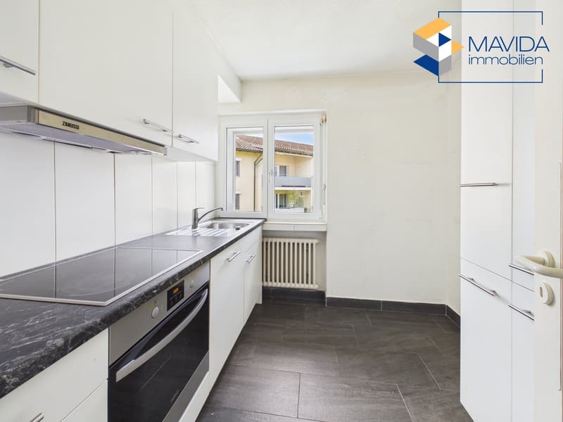 modern kitchen, white cabinets, black countertops, induction stove, oven, sink, window, radiator