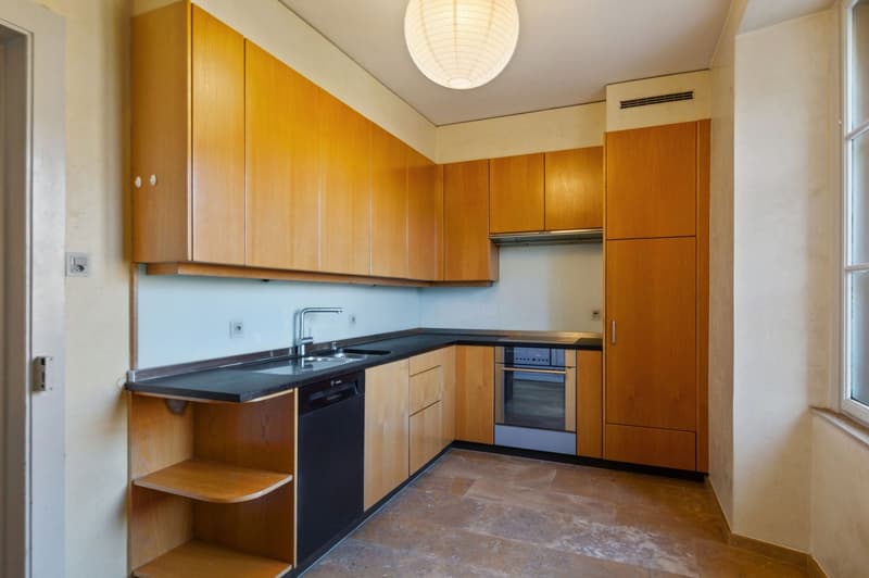 white tiles, wooden cabinets, black countertop, oven, dishwasher, sink, faucet, built-in appliances