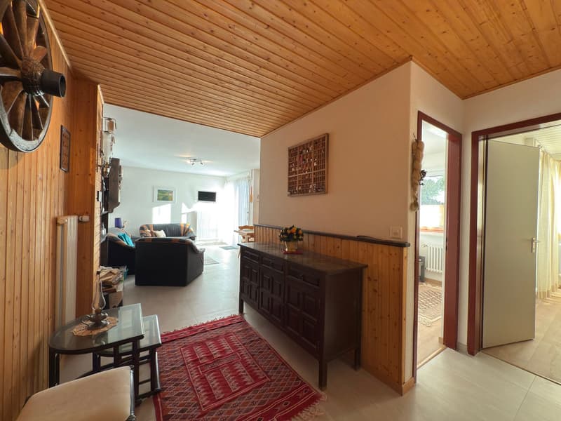 wooden ceiling, wooden paneling, tile flooring, glass table, couch, rug, wooden cabinet, flowers
