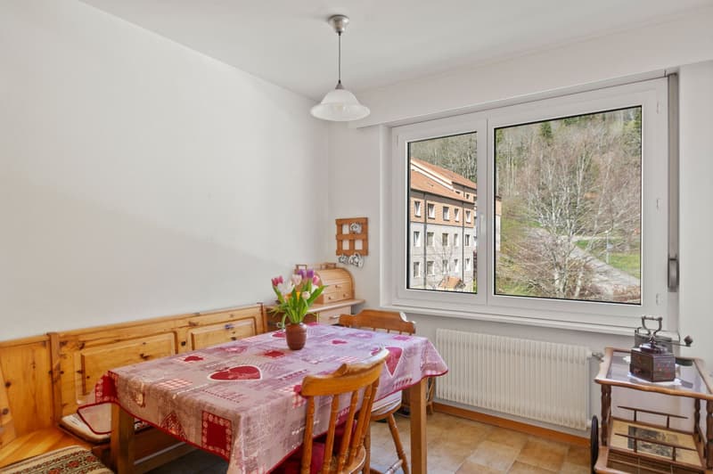 Wooden table, wooden chairs, flowers, radiator, large window