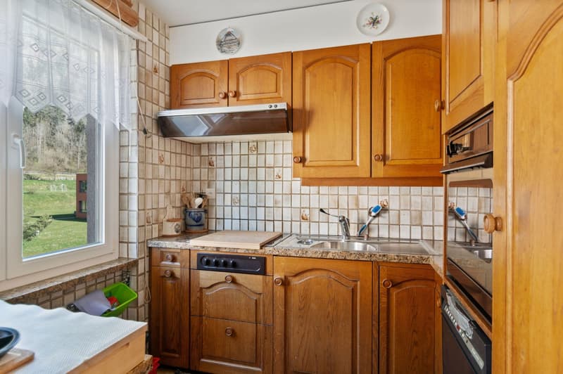 kitchen with window, tiled backsplash, wooden cabinets, granite countertop, kitchen sink, electric stove, dishwasher, kettle, cutting board, bowl, wine glass