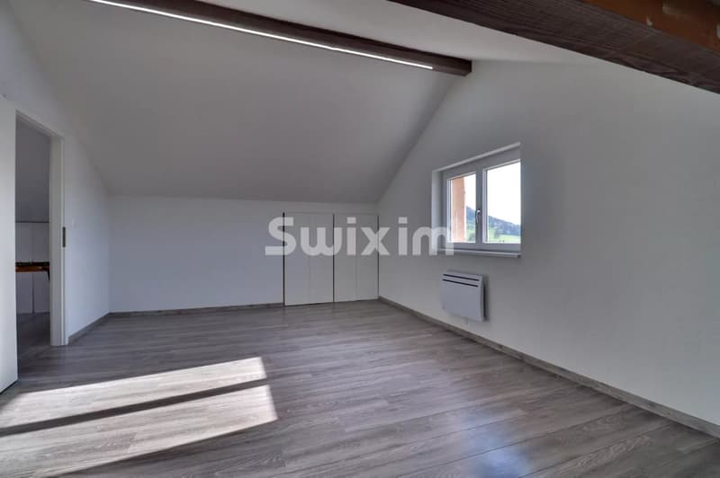 Salon lumineux avec grande fenêtre et parquet moderne.