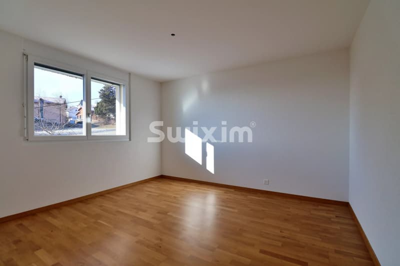 Chambre avec un sol en bois et une fenêtre laissant entrer la lumière naturelle.