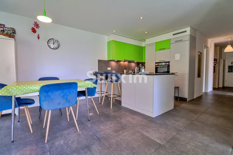 Cuisine moderne et lumineuse avec des meubles vert vif et un coin repas coloré.