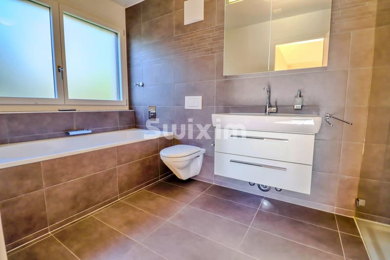Belle salle de bain moderne avec baignoire, lavabo double et toilettes suspendues.
