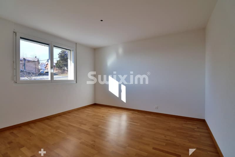 Chambre  avec un sol en bois et une fenêtre laissant entrer la lumière naturelle.
