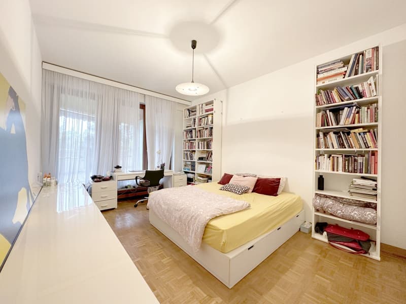 bed with yellow sheets, desk, bookcases, white curtains
