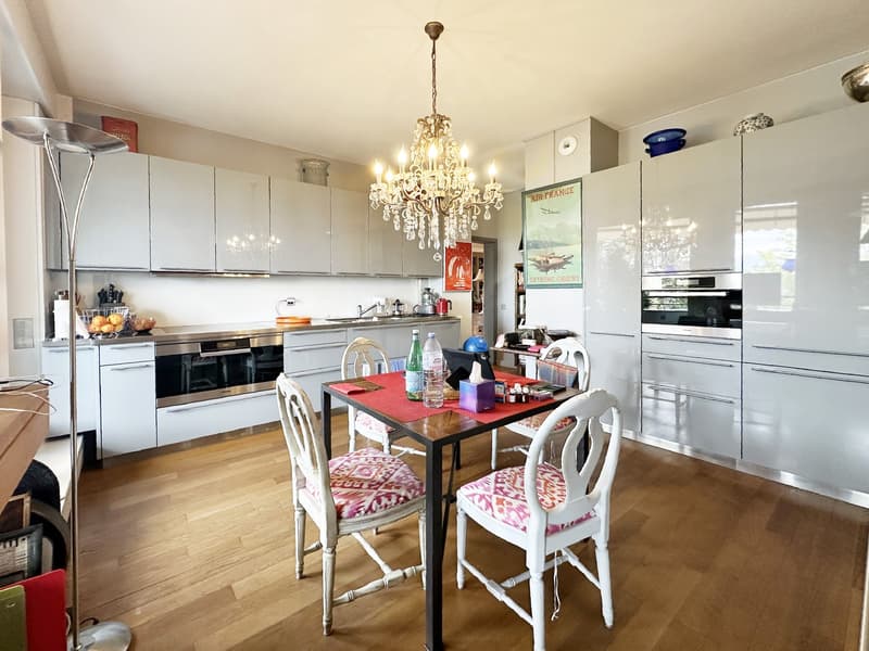 white cabinetry, chandelier, wooden floor, stainless steel appliances, table and chairs