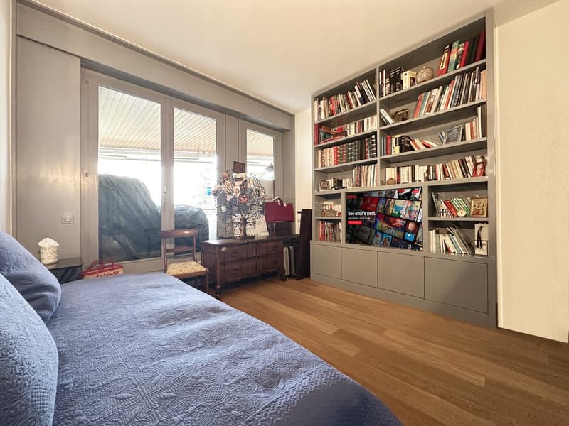 blue bed, wooden floors, bookshelf, double doors, glass windows, wooden chair, table, decorative objects