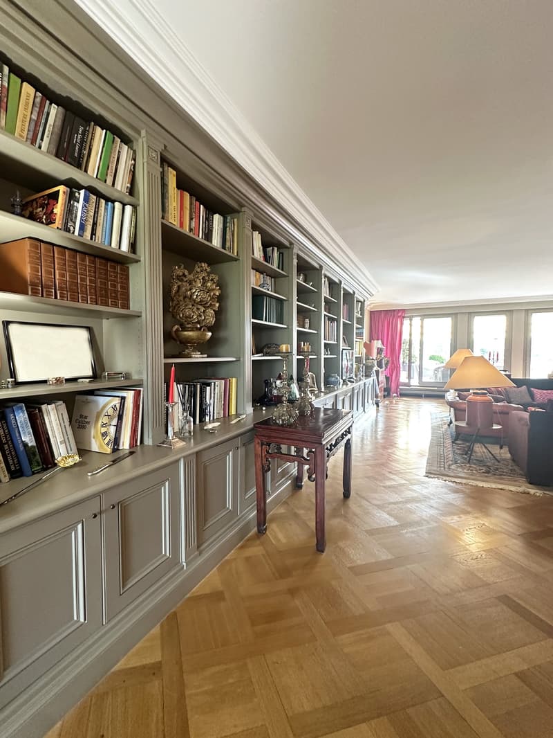 wooden floor, wall with bookshelves, decorative items, carpet, table, window, sofa