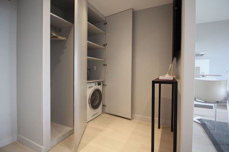 Laundry room with large built-in wardrobe and white washing machine