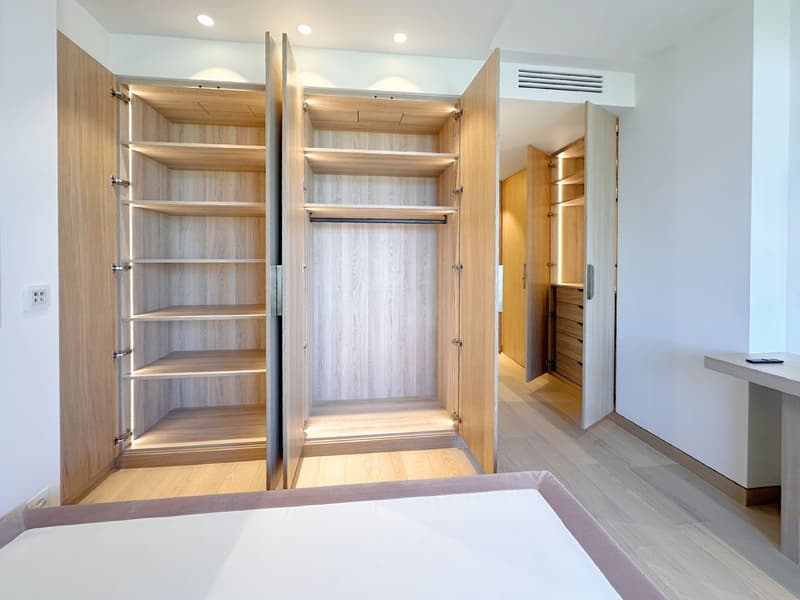 Spacious walk-in closet with wooden shelves, hanging space, and built-in drawers.