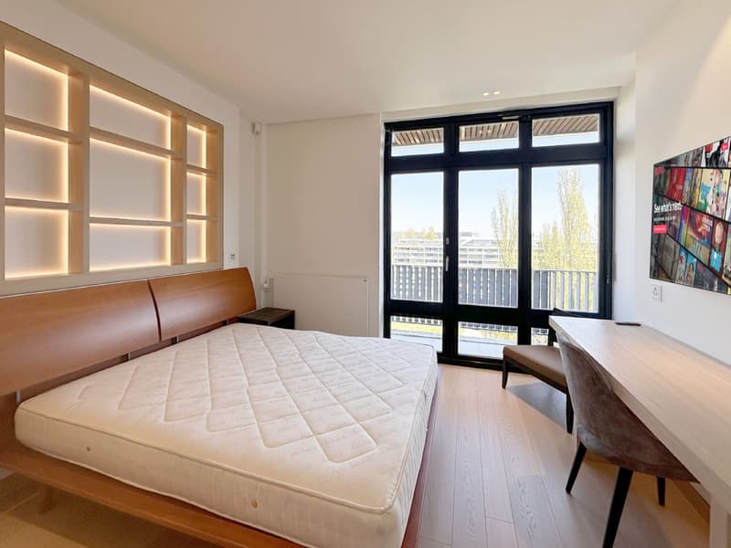 modern bedroom with wooden bed, large windows, wooden desk, chair, and a wall-mounted TV