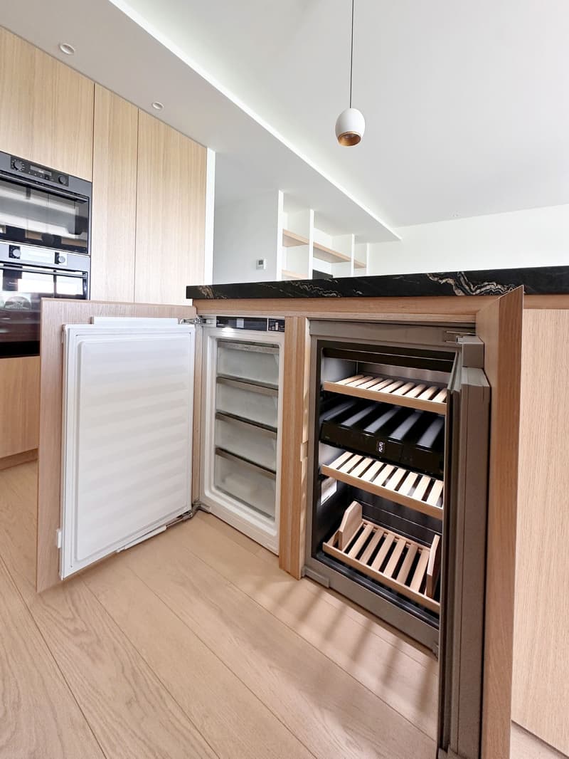modern kitchen, wooden cabinets, marble countertop, open refrigerator, wine cooler, wooden floors, hanging light