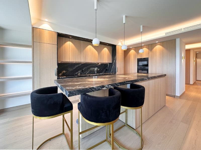 modern kitchen with marble countertop, wooden cabinets, black bar stools, pendant lights, built-in oven