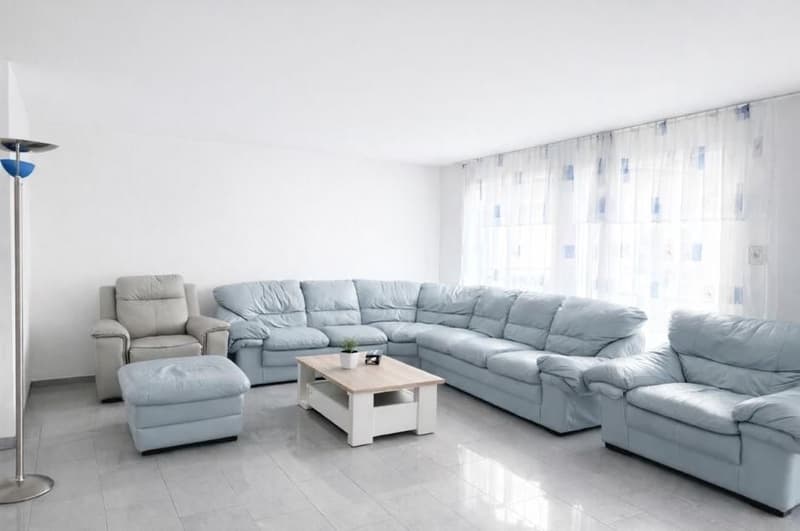 sectional couch, glass top coffee table, light gray walls, white tile floors, ottoman, floor lamp