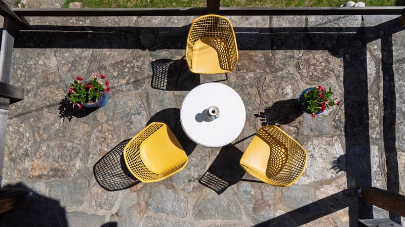 stone floor, yellow chairs, white table, flower pots, outdoor setting