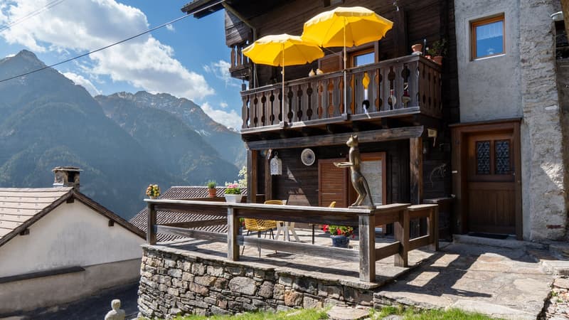 wooden house, stone wall, balcony with yellow umbrellas, terrace, mountain view
