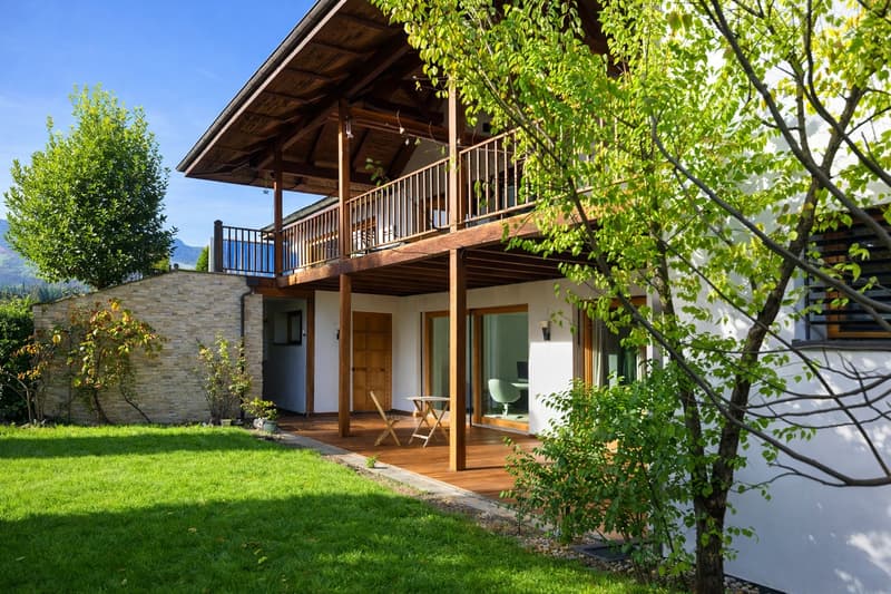 Detached house, wooden balcony, wooden deck, white walls, green lawn, trees