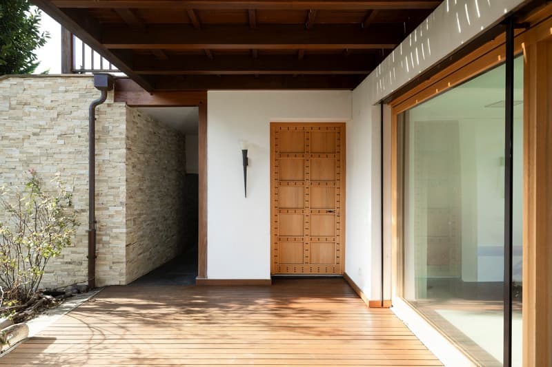 wooden deck, stone wall, large wooden door, glass wall, wall mounted light