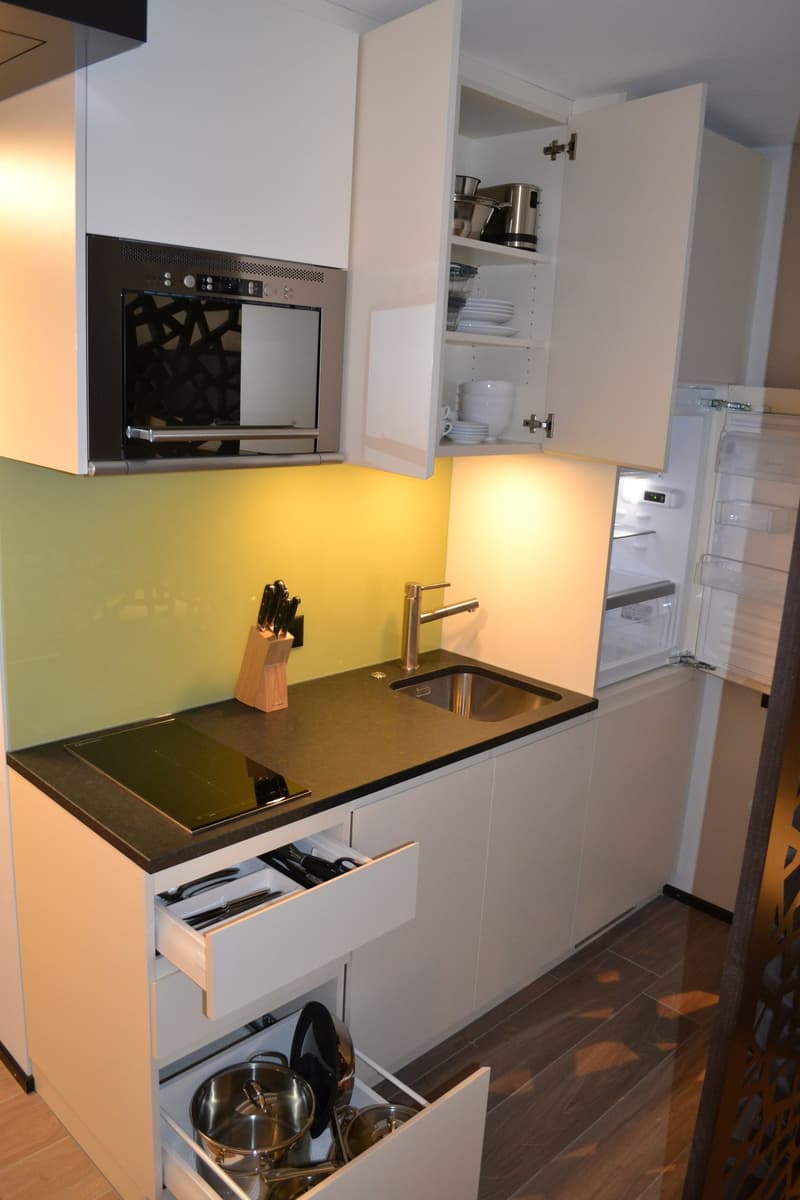 Modern kitchen with white cabinets, black countertop, built-in oven, and a dishwasher visible