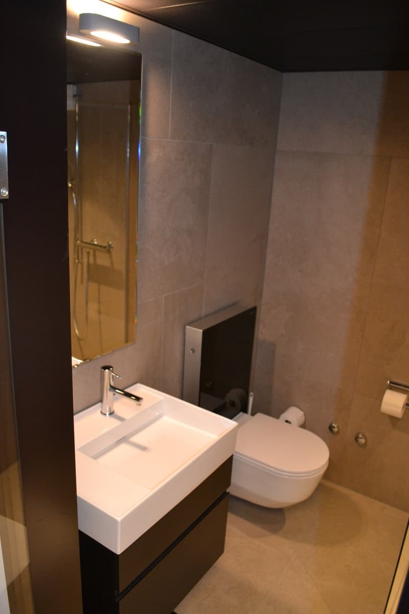 Modern bathroom with white sink, toilet, and tiled walls