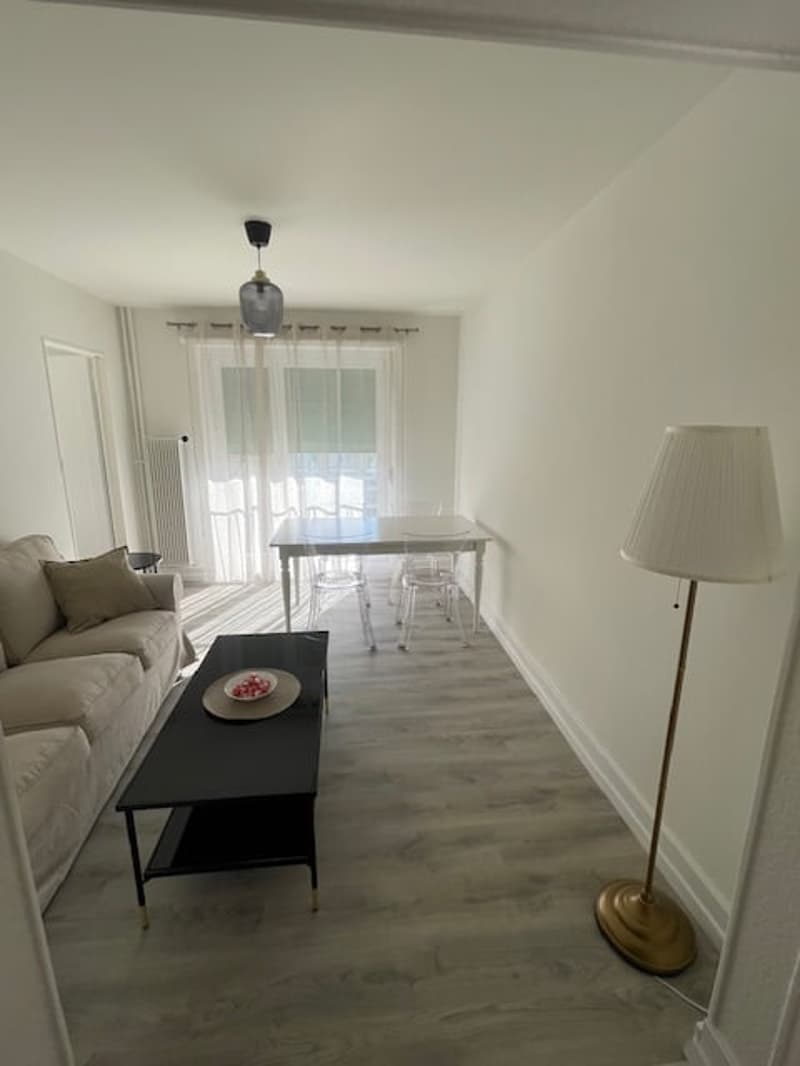 White walls, wooden flooring, couch, table, chair, floor lamp, table lamp