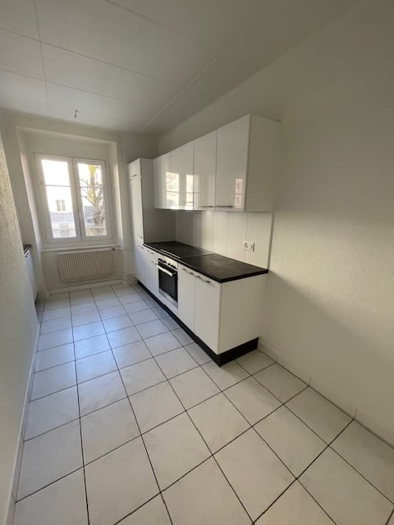 white cabinets, tiled floor, electric oven, black countertop, kitchen window