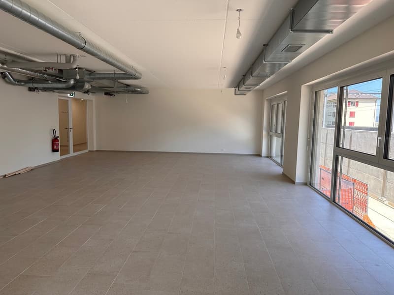 empty room, tiled floor, large windows, metal pipes on ceiling