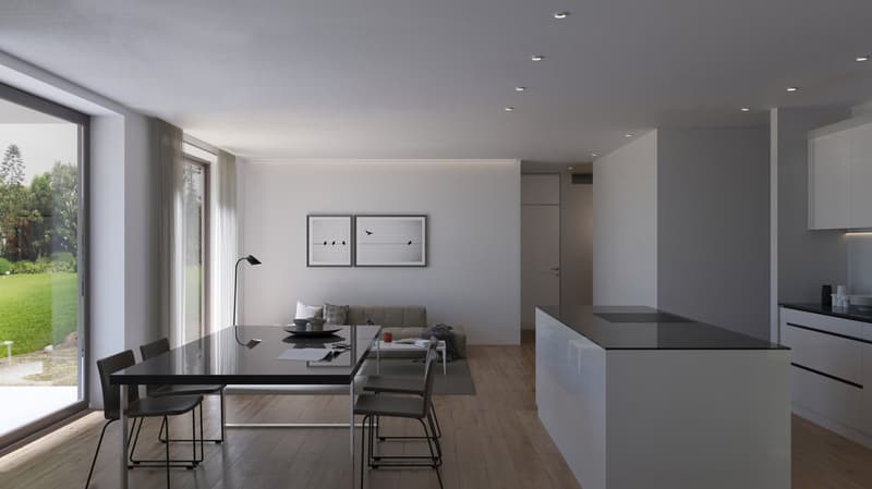 The image shows an open-concept living room and kitchen area with large windows overlooking a green outdoor space. The living room features a gray sofa and a black dining table with chairs. The kitchen has a sleek black countertop and minimalist cabinetry
