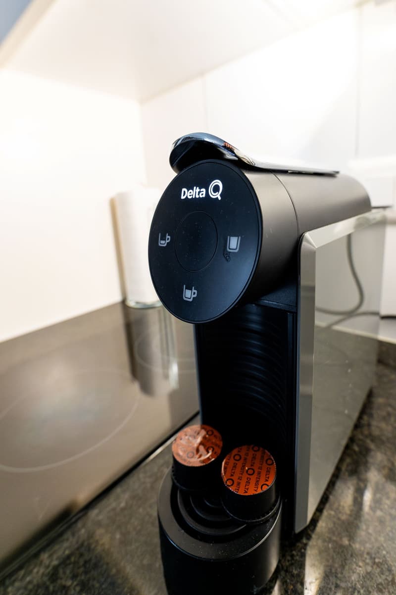 Black Delta Q coffee machine with control buttons and capsules