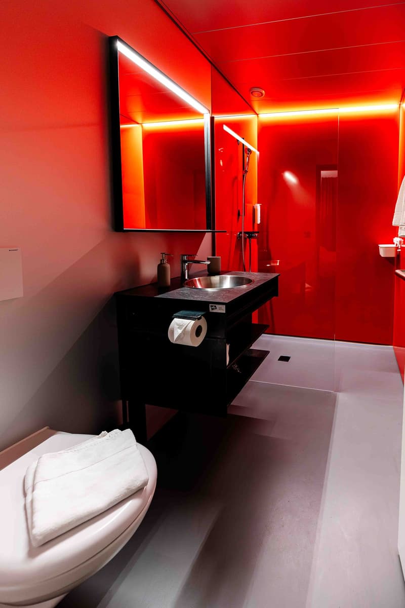 Bathroom with red walls, black vanity, silver sink, mirror, shower, toilet, towel, toilet paper
