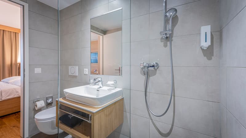 modern bathroom with shower, sink, toilet, wooden cabinet, tiled walls, wooden floor