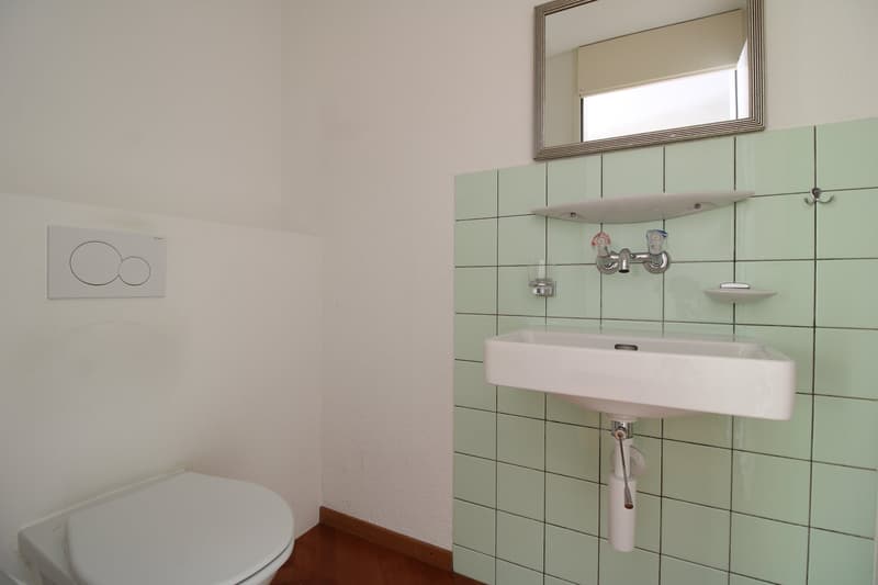 white sink, tiled wall, toilet, mirror