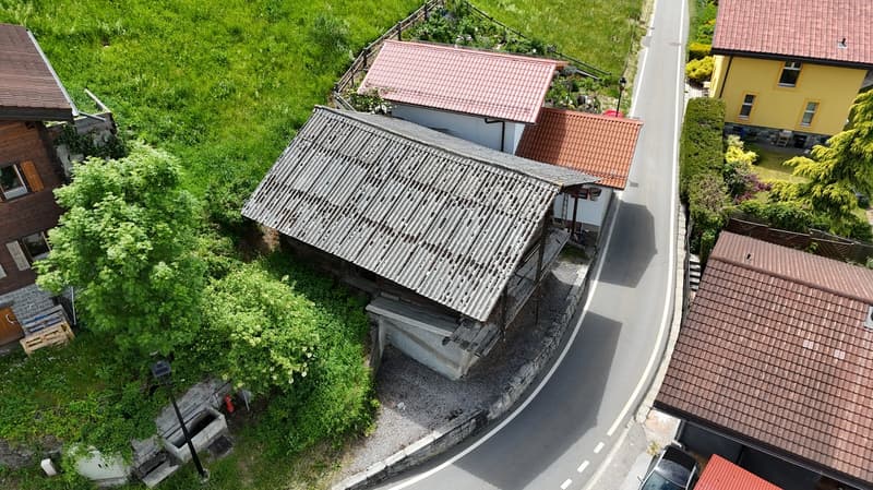 2 story house with red tile roof, surrounded by lush greenery and trees, with a balcony or terrace visible on the upper level.