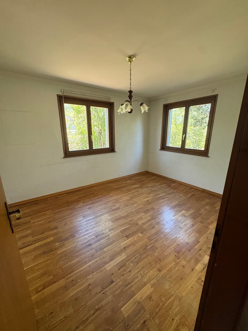 Empty room, wooden floor, white walls, two windows, chandelier on the ceiling