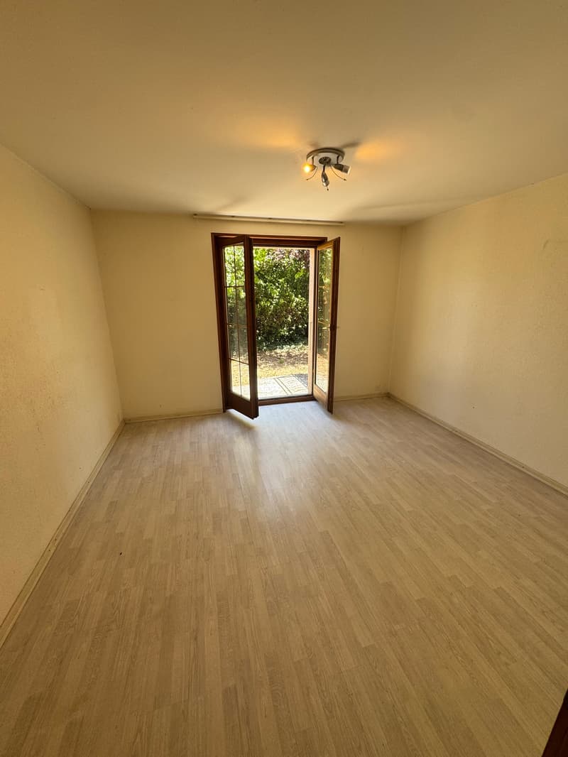 Empty room, wooden floor, sliding door to outside, beige walls, ceiling light