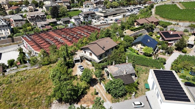 Complex of houses, large detached property with several homes, red roof, brown roofs, large solar panels, white car parked in front