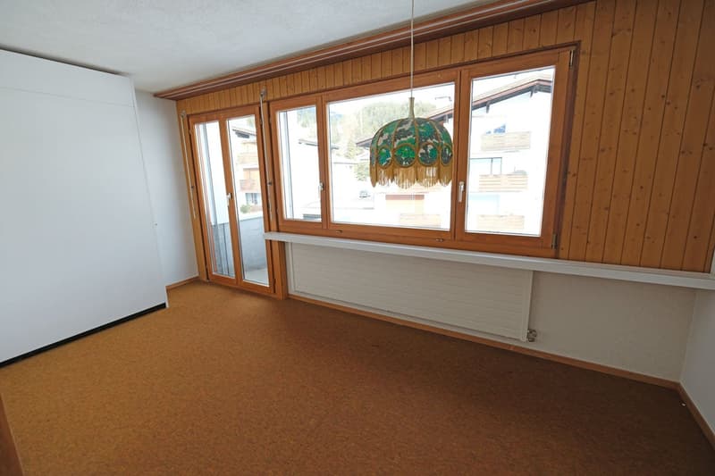 empty room with windows, a white radiator, brown carpet, wooden walls, sliding doors