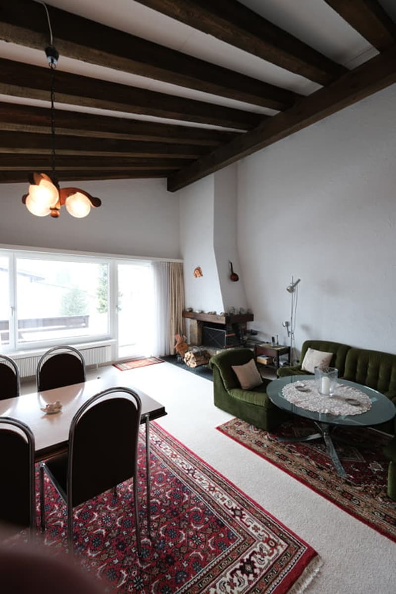 wooden ceiling, fireplace, dining table, green couch, carpet, lamp