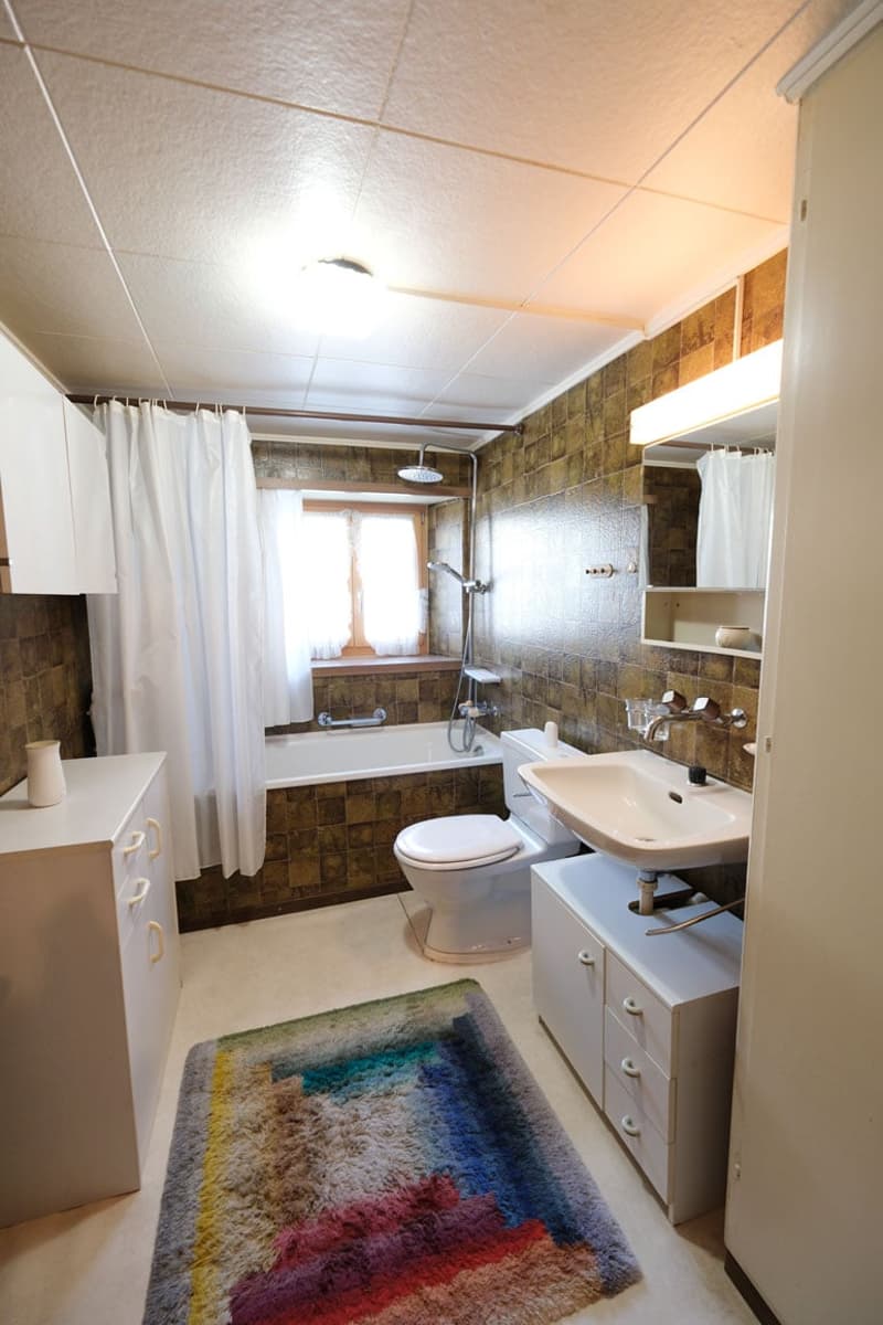 Bathroom with bathtub, toilet, sink, shower, mirror, cabinets, rug, and window