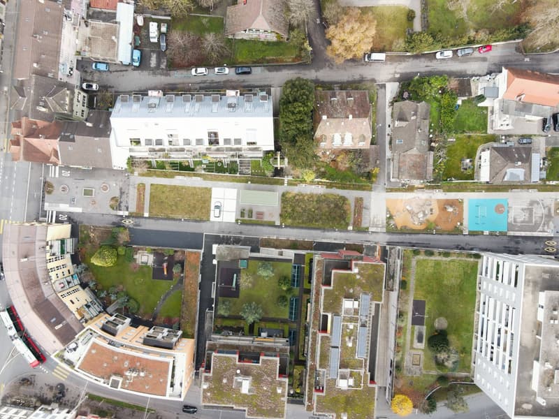 Overview of residential area with buildings, roads, parking areas, and greenery