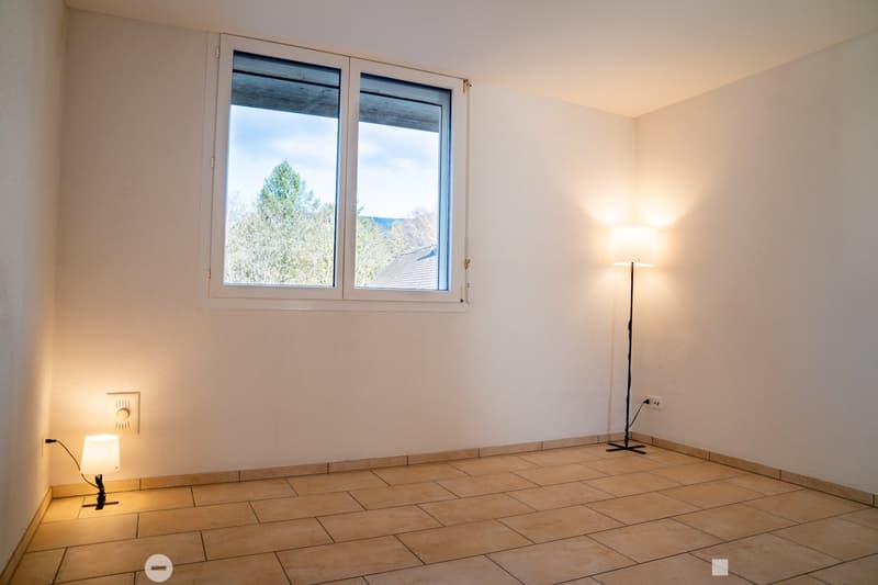 empty room with white walls, beige tiles, floor lamp, wall lamp, window with trees outside