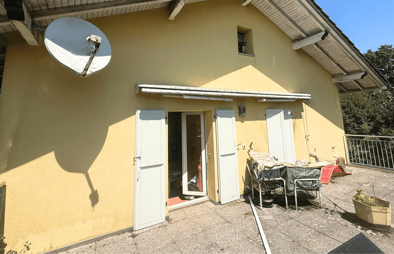Yellow house with satellite dish, two open white doors, small balcony, potted plant