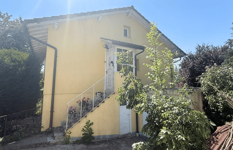 2 story yellow house, metal fence, white windows, small staircase leading to the entrance