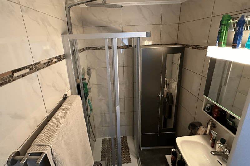 tiled floor, white shower, sink, medicine cabinet, towel rack